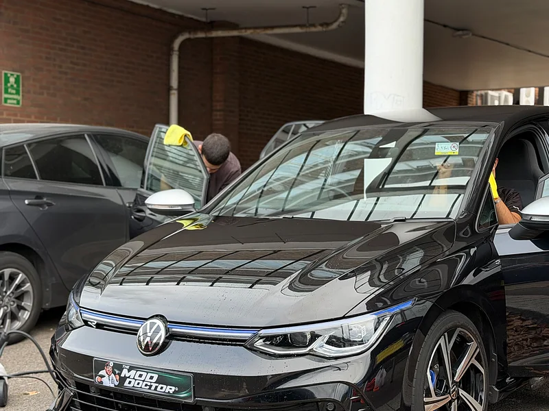 A technician working on the glass of a black Golf R on site