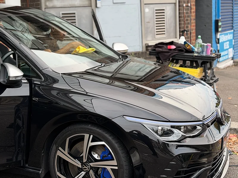 A black Golf R on a driveway with the mobile detailing kit set up beside it