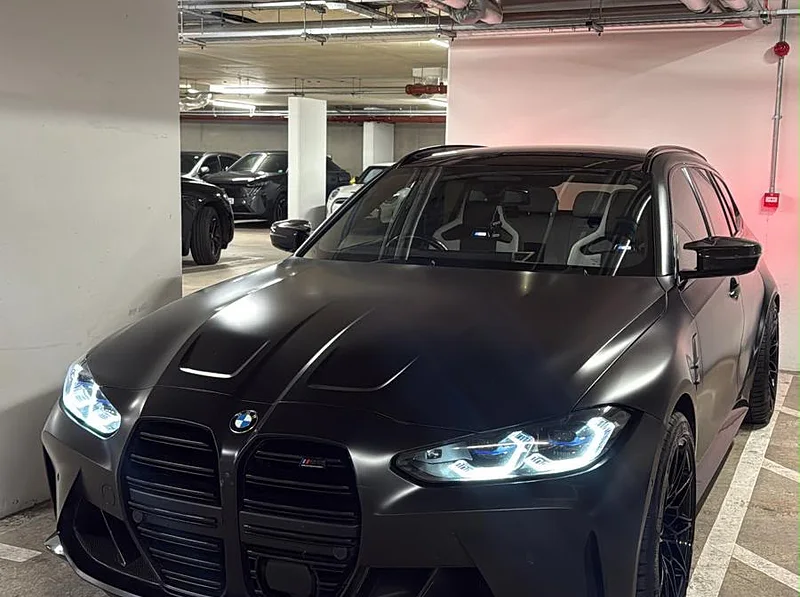 A blacked-out BMW M3 Touring lit in an underground car park